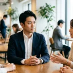 会議で相手の意見を聞きながら自分の考えを整理する男性。メタ認知によるコミュニケーション能力向上のイメージ